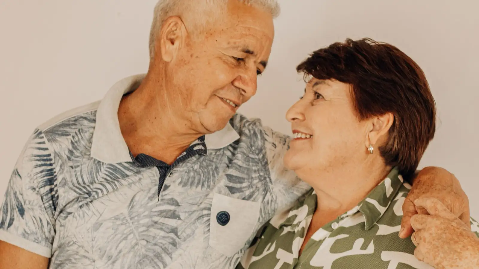 Una pareja adulta se mira sonriendo, uno con la mano sobre el hombro del otro